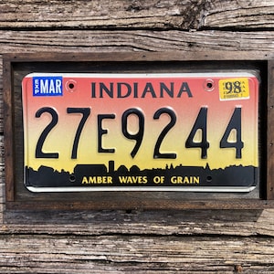 May include: A framed Indiana license plate with the number 27E9244 and the slogan "Amber Waves of Grain".