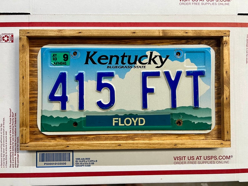 May include: A Kentucky license plate with the number 415 FYT and the word "FLOYD" printed below. The plate is framed in a wooden frame.