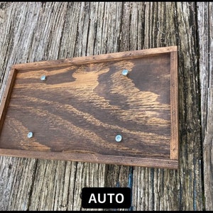 May include: A wooden sign with a dark brown stain and a natural wood frame. The sign has four silver screws holding it together. The sign says "AUTO" in white letters.