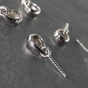 May include: Five silver-toned pendant bails with a twisted wire loop. The bails are designed for attaching charms or pendants to necklaces or bracelets.