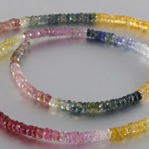 May include: A multi-colored gemstone necklace with beads in shades of pink, red, yellow, blue, and green.