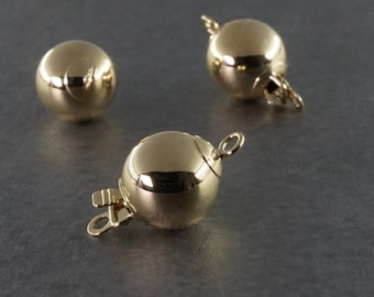 May include: Three gold-toned ball clasps for necklaces or bracelets. Each clasp has a round ball shape with a spring-loaded mechanism.