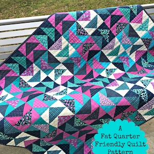 May include: A quilt pattern called "Blackberry Twirl" by Jane Michel Quilt Designs. The quilt is made with a variety of fabrics in shades of pink, blue, and white. The quilt is a fat quarter friendly pattern and measures 48 inches by 60 inches. The quilt is displayed on a white bench.