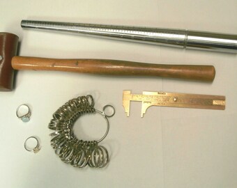 May include: A set of jewelry making tools including a ring sizer, a ring mandrel, a jeweler's hammer, and a caliper.