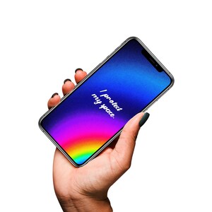 Pode incluir: Um smartphone com um ecrã gradiente colorido, que transita do azul para o roxo e para tons de arco-íris. O ecrã exibe o texto "I protect my space". O telemóvel é segurado numa mão com verniz escuro.