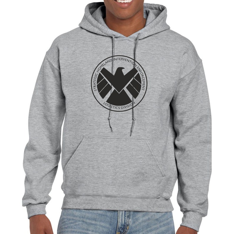 May include: A gray hooded sweatshirt with a black logo on the front. The logo is a circle with the words "Strategic Homeland Intervention Enforcement Logistics Division" around the outside and a black falcon inside.