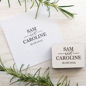 May include: A wooden stamp with the text "SAM and CAROLINE 16.08.2025" in black lettering.