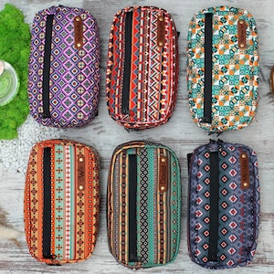May include: Six colourful zippered pouches with geometric patterns and personalised names. The pouches are made of fabric and have a black zipper. The names on the pouches are "Isabella", "Elizabeth", "Olivia", "David", "Megan", and "Olivia".