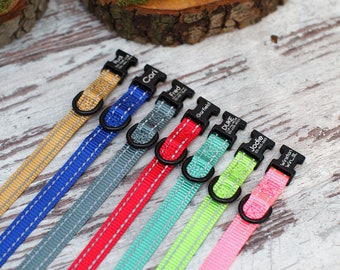 May include: Eight colorful dog collars with personalized names on the buckles. The collars are made of a reflective material with a black stitching detail. The collars are arranged in a row on a white wooden surface.