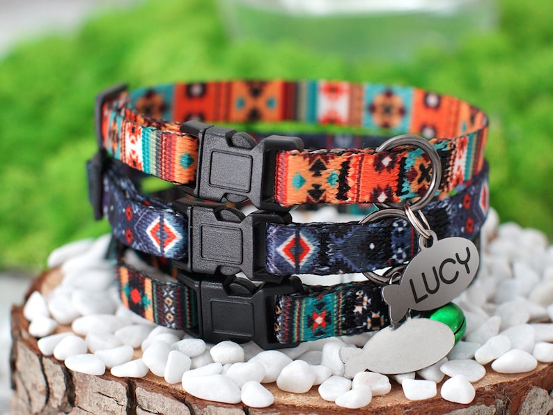 May include: Three colourful patterned cat collars with black buckles and a silver tag that says "LUCY".