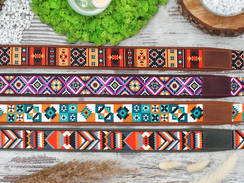 May include: Four colorful camera straps with geometric patterns. The straps are made of fabric and have a leather or suede backing. The patterns include orange, blue, green, purple, and white.