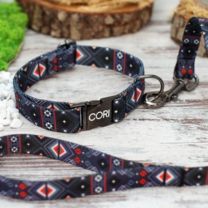 K&ouml;nnte beinhalten: Ein schwarzes und blaues Hundehalsband und eine Leine mit geometrischem Muster. Das Halsband hat eine schwarze Metallschnalle mit dem eingravierten Wort "CORI".