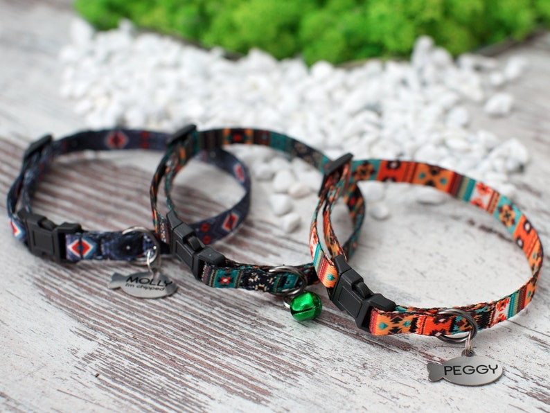 May include: Two colorful cat collars with adjustable buckles and a bell. One collar has a tag that says "MOLLY" and the other says "PEGGY".