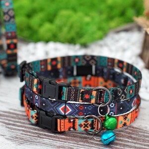 May include: Three colorful cat collars with a geometric pattern in shades of blue, orange, and black. The collars have adjustable buckles and a small bell charm.
