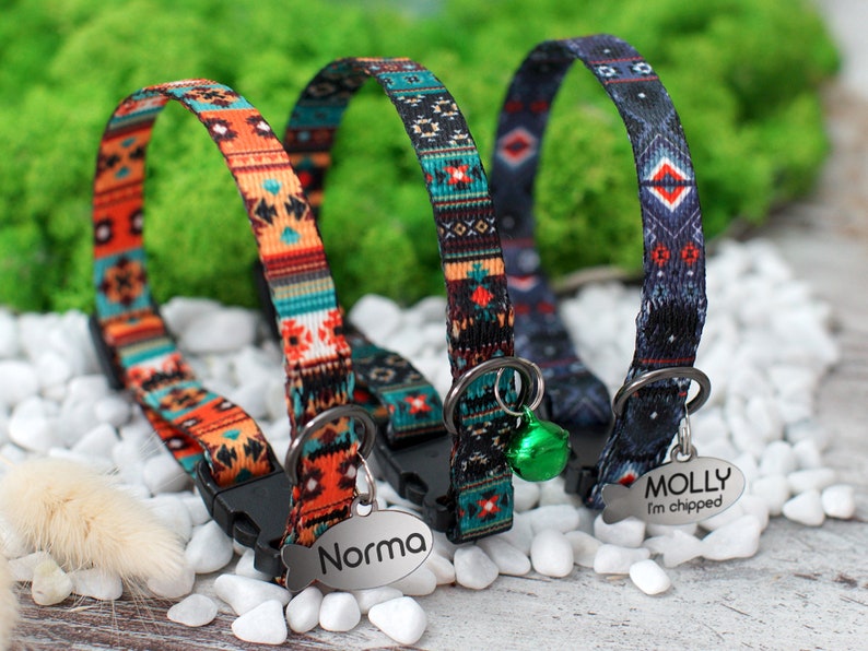 May include: Three colorful cat collars with a geometric pattern. The collars have a metal tag with the names "Norma" and "Molly I'm chipped" engraved on them.