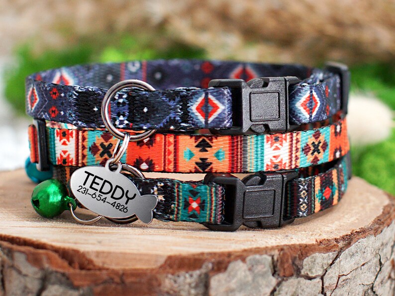 May include: A set of three colorful cat collars with a geometric pattern. The collars have a black buckle and a silver tag that reads "TEDDY 231-654-4826".