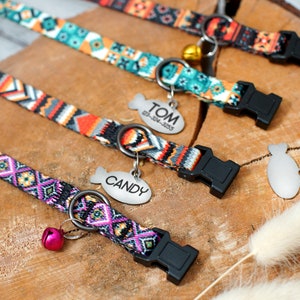 May include: Four colorful dog collars with adjustable buckles and metal fish-shaped tags. The tags are engraved with the names "TOM", "CANDY", and two blank tags. Each collar has a bell attached.