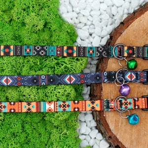 May include: Three colorful patterned dog collars with bell charms. The collars are black, blue, and orange with geometric designs. The bells are green, purple, and silver.