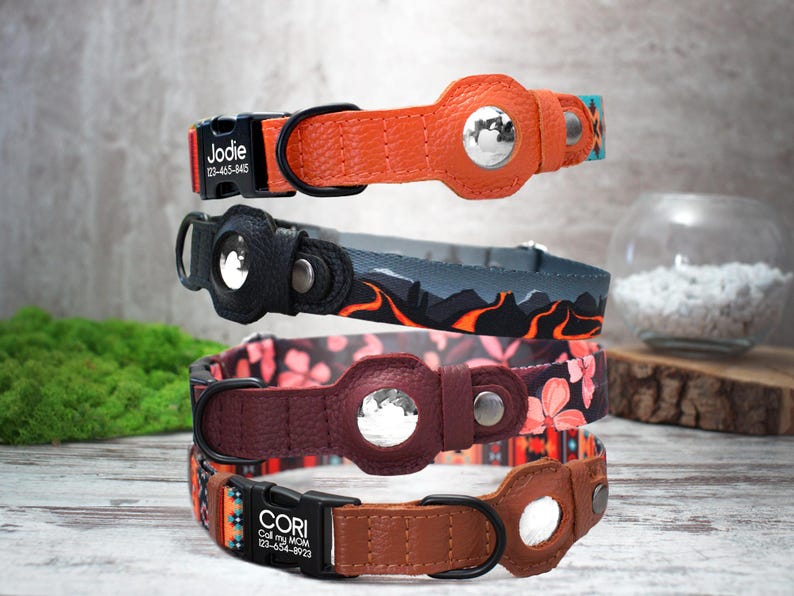 Peut inclure: Quatre colliers pour chien empil&eacute;s les uns sur les autres. Les colliers sont en cuir et pr&eacute;sentent diff&eacute;rents motifs et couleurs. Le collier du haut est orange avec une boucle noire et le texte "Jodie 123-456-8465". Le deuxi&egrave;me collier est noir avec un motif gris et orange. Le troisi&egrave;me collier est bordeaux avec un motif floral. Le collier du bas est marron avec un motif color&eacute; et le texte "CORI Call my MOM 123-456-8923".