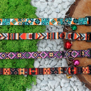 May include: Four colorful patterned cat collars with black buckles and bell charms. The collars feature geometric designs in shades of orange, teal, purple, and black.