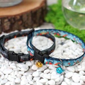 May include: Two colourful cat collars with bells. One collar is black with orange and white accents, the other is blue with orange and white accents. Both collars have black plastic buckles.