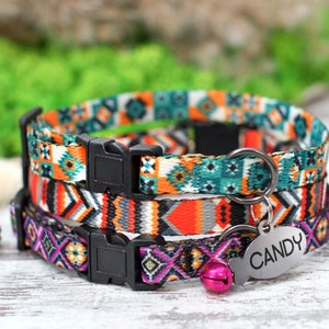 Op de afbeelding: Drie kleurrijke kattenhalsbanden met geometrische patronen. De halsbanden liggen op elkaar. De bovenste halsband is turquoise, wit en oranje. De middelste halsband is oranje, grijs en zwart. De onderste halsband is paars, roze en zwart. Elke halsband heeft een zwarte plastic gesp en een zilveren metalen ring. De onderste halsband heeft een roze bel en een zilveren label met de tekst "CANDY".