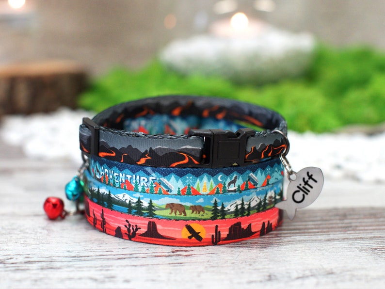 May include: A colourful cat collar with a mountain and forest design. The collar has a black buckle and a silver tag that says "Cliff".
