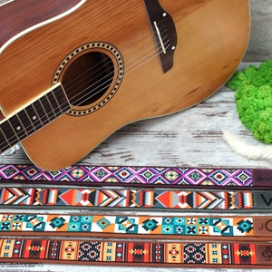 May include: Four colorful guitar straps with geometric patterns. The straps have leather ends with the names "Jennifer", "W", "JGT", and "S" embossed on them.
