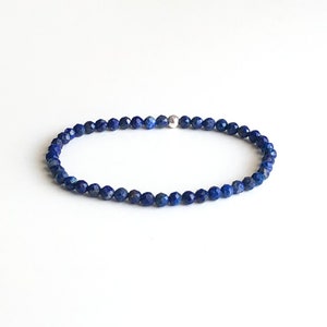 May include: A blue gemstone bracelet with a silver bead clasp. The bracelet is made of small, faceted beads.