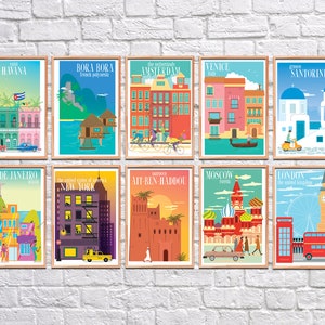 May include: A set of ten colorful travel posters featuring iconic landmarks and cityscapes from around the world. Each poster includes the city name, country, and a small illustration of a local landmark or symbol. The posters are framed in a light wood frame.