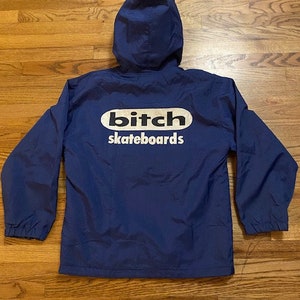 May include: A navy blue hooded jacket with a white oval logo that says "Bitch skateboards".