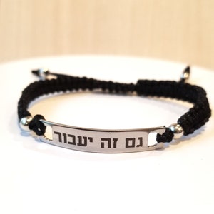 May include: Black braided bracelet with a silver rectangular tag that reads "עם ה' ישוע" in Hebrew.
