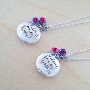 May include: Two silver locket necklaces with a silver chain. Each locket has a different inscription: "I love you, sis!" and "I love you,  quies!" Each locket has a pink and purple crystal charm.