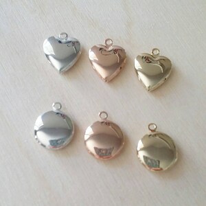May include: Six locket pendants in different finishes: silver, rose gold, and gold. Three are heart-shaped and three are round.