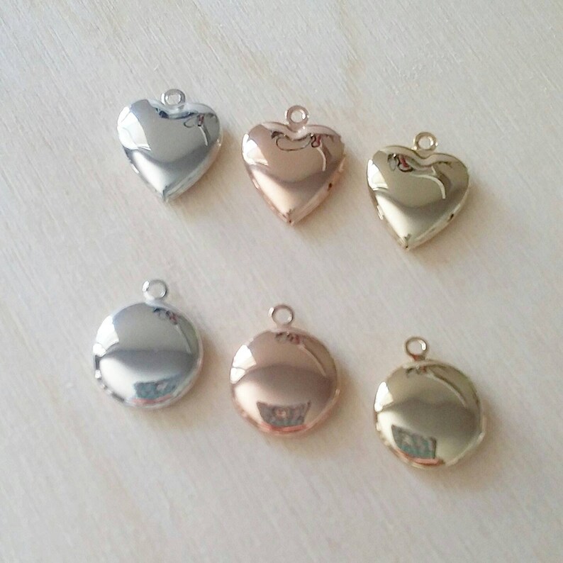 May include: Six locket pendants in different finishes: silver, rose gold, and gold. Three are heart-shaped and three are round.
