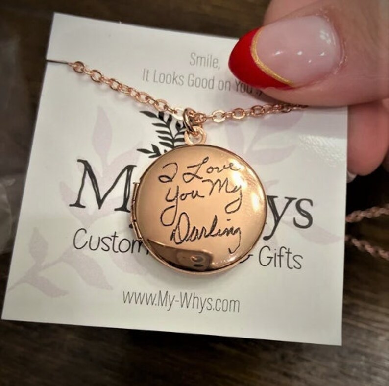 May include: A gold locket necklace with a handwritten message that reads "I Love You My Darling". The necklace is on a white card with the text "Smile, It Looks Good on You" and "Custom Gifts".