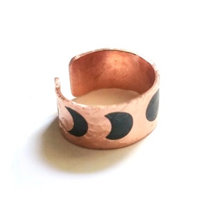 Peut inclure: Une bague en cuivre avec une texture martelée et des motifs de croissants de lune noirs.