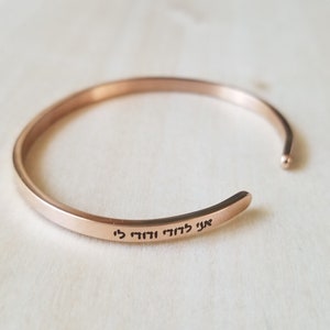 May include: A rose gold bangle bracelet with the Hebrew phrase "Ani L'dodi V'dodi Li" engraved on the inside.
