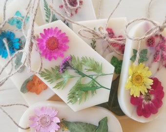 Puede incluir: Surtido de seis fundidos de cera con flores y hojas prensadas. Los fundidos son de varias formas y tamaños, incluyendo rectangulares, ovales y hexagonales. Las flores son en tonos de rosa, amarillo, azul y rojo.