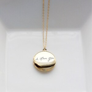 May include: A gold chain necklace with a round locket pendant. The locket is engraved with the handwritten message "I love you".