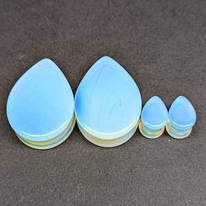 Op de afbeelding: Set van vier traanvormige opalite plugs in verschillende maten. De plugs zijn lichtblauw van kleur met een witte, iriserende glans.