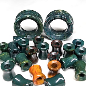 May include: A set of green and red jasper stone ear gauges, including a pair of large circular gauges and several smaller gauges in various sizes. The gauges are made of natural stone and have a unique speckled pattern.
