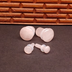 May include: Set of four pink rose quartz ear gauges, two larger gauges and two smaller gauges.