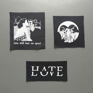Op de afbeelding: Drie zwarte stoffen patches met witte zeefdrukafbeeldingen. Eén vierkante patch toont een kussend stel met de tekst "love will tear us apart". Een andere vierkante patch toont twee skeletten die een milkshake delen. Een rechthoekige patch toont "HATE" boven "LOVE".