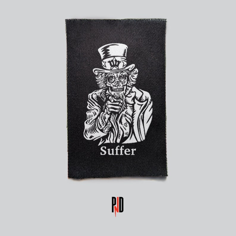 May include: Black and white embroidered patch featuring a skeletal Uncle Sam figure with a top hat and the word "Suffer" below.