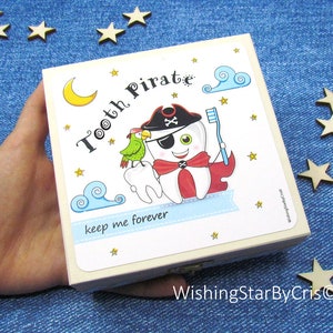 May include: A white wooden box with a colorful illustration of a tooth pirate holding a toothbrush. The box has the text "Tooth Pirate" and "keep me forever" on it. The box is perfect for storing lost teeth.