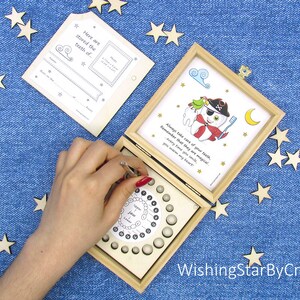 May include: A wooden box with a tooth fairy theme. The box has a compartment for storing baby teeth and a removable card with a tooth chart. The card also has a space for a photo and a message. The box is decorated with a pirate tooth character and the text "Always take care of your teeth, Remember that they are magical! Every time that you smile, you warm my heart."