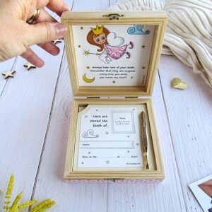 May include: A wooden box with a pink and white polka dot design. The box is open and has a picture of a fairy with a tooth inside. The box is for storing baby teeth. The text on the box says "Always take care of your teeth, remember that they are magical - every time you smile, you warm my heart!" and "Here are stored the teeth of..."