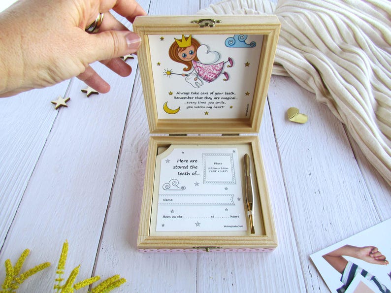 May include: A wooden box with a pink and white polka dot design. The box is open and has a picture of a fairy with a tooth inside. The box is for storing baby teeth. The text on the box says "Always take care of your teeth, remember that they are magical - every time you smile, you warm my heart!" and "Here are stored the teeth of..."