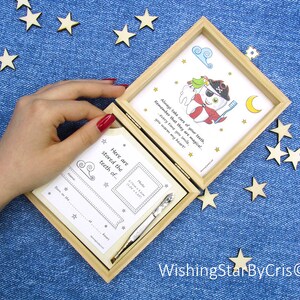 May include: A wooden box with a white card inside. The card has a cartoon illustration of a tooth with a pirate hat and a toothbrush. The text on the card reads "Always take care of your teeth, remember that they are magical... every time you smile, you warm my heart!" The box is open and there is a smaller white card inside with the text "Here are stored the teeth of..." and a space for a photo and information about the child.